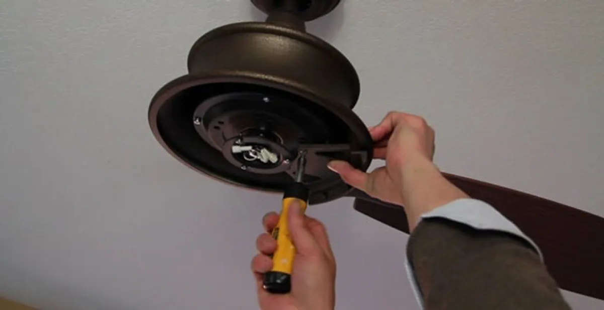 Electrician installing ceiling fan mounting bracket and fixture in Littleton, CO