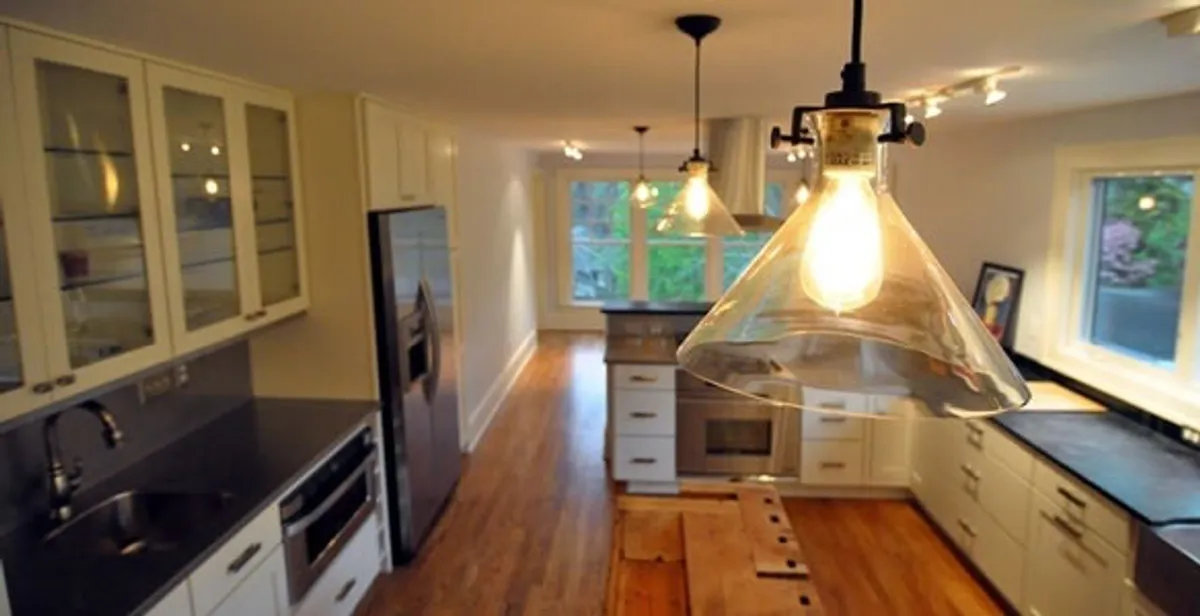 Residential electrician installing modern indoor light fixture in a home in Littleton, CO