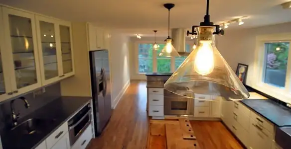 Residential electrician installing modern indoor light fixture in a home in Littleton, CO