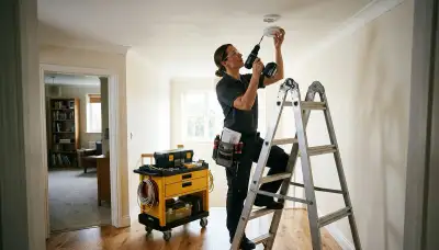 Electrician installing a wired smoke detector in a Littleton, CO home